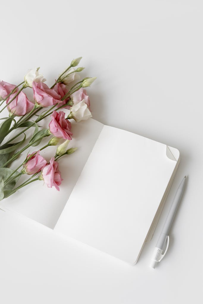 Open notebook with pink and white flowers and a pen. Perfect for minimalistic designs.